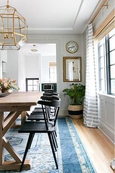 a dining room table with chairs and a clock on the wall