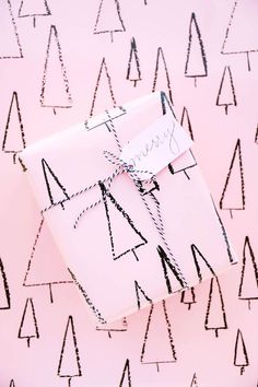 a wrapped gift box on a pink background with black and white trees drawn on it