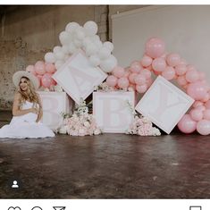 a woman sitting on the floor in front of balloons and letters that spell out baby