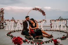 a man and woman sitting on the ground in front of a sign that says love