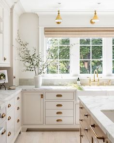 a kitchen filled with lots of white counter tops and wooden shelves next to a window