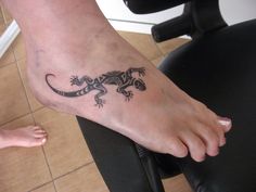 a lizard tattoo on the foot of a person