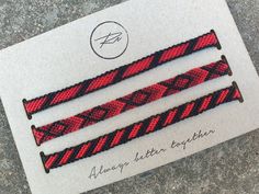 three red and black braided bracelets sitting on top of a piece of paper