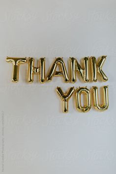 the word thank you spelled out in gold balloon letters on a white background by julia radwell for stocksy united