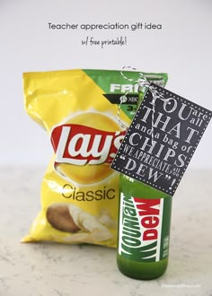 a bag of chips sitting next to a bottle of soda on top of a counter