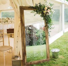 a large mirror sitting on top of a grass covered field next to a white tent