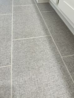 a bathroom with gray tile floors and white cabinets