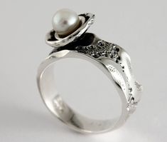 "Here is the ring \"Flower of sea\" in sterling silver and white freshwater pearl. Each ring is unique, the lace around the dome that hosts the pearl is unique each time and may be different from the photo. Size: 7 mm width (9/32 in) Material: Sterling silver and white freshwater pearl The unique texture of the ring is made from a molding of a sea urchin shell symbolizing a footprint of good times. This organic texture was handcrafted by the jeweler Marie-Eve Bordeleau of Trois-Rivières, Quebec, Canada. Included: -A polishing cloth -A bookmark about the collection -A rigid box ** Shipping fees are free in Canada and the United States Inspiration: The shell of the sea urchin inspires emotions, feelings and memories. The unique impressions left by the shells symbolize a true story, a trip or Unique White Pearl Ring, Unique Sterling Silver Pearl Promise Ring, Sterling Silver Open Pearl Ring, Sterling Silver Open Pearl Ring Fine Jewelry, Silver Sterling Silver Pearl Ring For Wedding, Unique Sterling Silver Pearl Ring For Formal Occasions, White Gold Sterling Silver Open Pearl Ring, Unique Pearl Ring Jewelry, Elegant Silver Pearl Ring Stamped 925