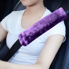 a woman sitting in the back seat of a car with a purple pillow on her arm