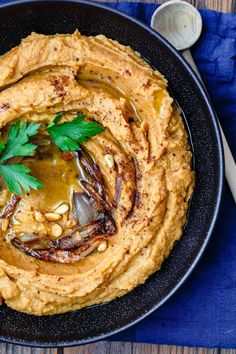 hummus in a black bowl with garnish on top