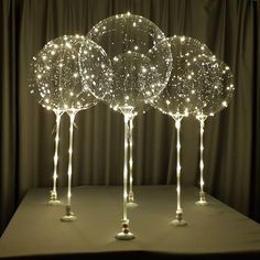 three lighted balls on top of each other in the shape of trees with long legs