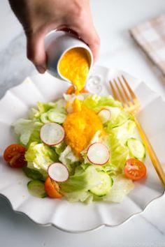 a person pouring dressing onto a salad on a plate