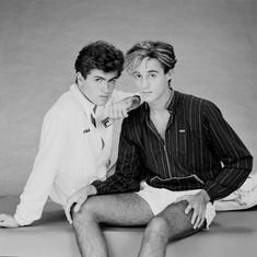 black and white photograph of two people sitting on the ground with one person wearing shorts