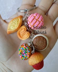 a hand holding a keychain that has different types of food items on it