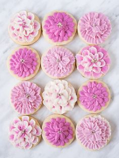 decorated cookies with pink and white icing on a marble counter top, arranged in the shape of flowers