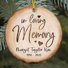 a personalized ornament hanging from a pine tree with the words in loving memory