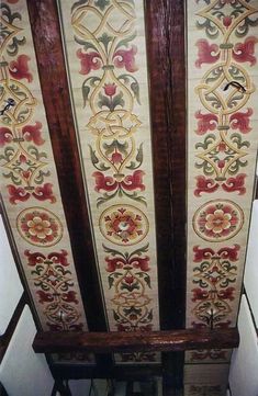 an ornately decorated ceiling in the corner of a room with white walls and wood trimming