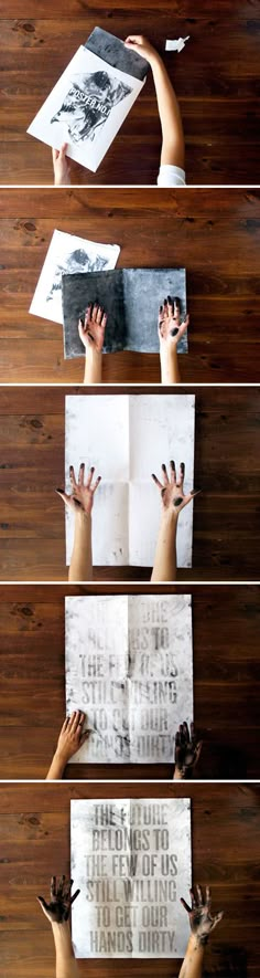 hands reaching out from the pages of an open book on a wooden table with other hand prints