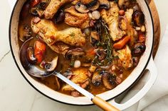 a pot filled with chicken, mushrooms and carrots on top of a white counter