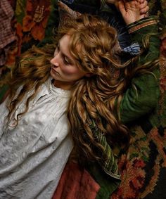 a woman laying on the ground with her hair blowing in the wind