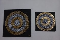 two black and gold paintings hanging on the wall