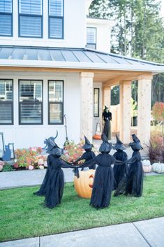 a group of witches sitting on top of a lush green field next to a house