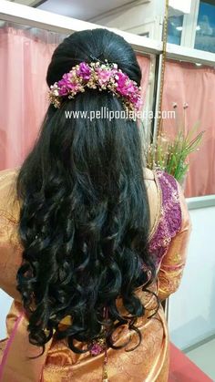 the back of a woman's head with long hair and flowers in her hair