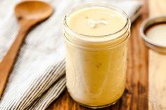 a jar filled with liquid sitting on top of a wooden table next to spoons