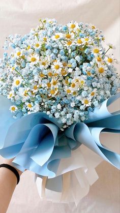 a bouquet of blue and white flowers in someone's hand