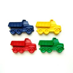 three different colored plastic toys trucks on a white surface with one red, one green and one blue