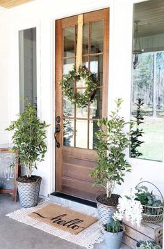 two potted plants are on the front porch with a welcome mat and doormat