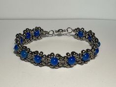 Blue and silver glass flower beaded wire wrapped bracelet 7.5 inches magnetic closure Beaded Metal Crystal Bracelet, Silver Beaded Flower Jewelry, Silver Czech Glass Jewelry With Spacer Beads, Handmade Metal Beaded Bracelets With Round Beads, Handmade Metal Crystal Bracelet With Round Beads, Silver Flower Jewelry With Spacer Beads, Silver Hematite Round Beads Jewelry, Silver Hematite Jewelry With Round Beads, Silver Wire Wrapped Beaded Bracelets