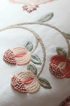 an embroidered pillow with flowers and leaves on it