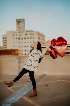 a woman holding onto some red balloons in the air with buildings in the back ground