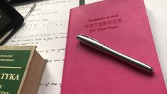 a pink notebook with a pen on top of it