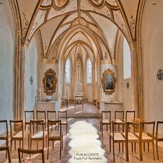 the inside of an old church with wooden chairs and paintings on the walls, along with stone flooring