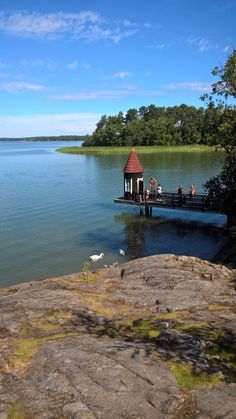 a small pier on the edge of a body of water with people standing on it