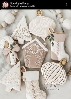 christmas cookies decorated with white and gold decorations on a marble countertop next to ornaments