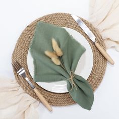 the place setting is ready to be served with green napkins, silverware and forks