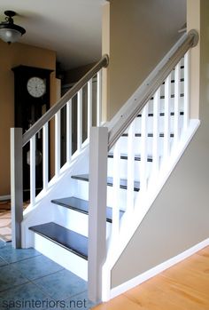 there is a clock on the wall next to the stairs in this house with tile flooring