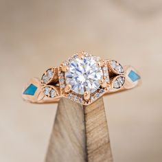 a diamond and blue stone ring sitting on top of a piece of wood