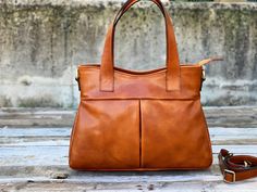 "This Brown cowhide leather bag is 100% handmade. this large tote bag is suitable for carrying everything in your everyday life. It has a Zipper Closure and Cross-Body strap. The bag has a cotton lining and it has 3 inner pockets. as you can see it made by really high-quality Italian leather.this leather calls \"Pelle Conciata Al Vegetale\", which means that the leather is tanned with only natural materials. Dimentions: - Width ( top of the bag ) : 32 Cm / 12.5'' ( Bottom of the bag ) : 37 Cm / Handmade Brown Shoulder Bag For On-the-go, Cognac Large Capacity Tote Shoulder Bag, Handmade Leather Shoulder Bag For On-the-go, Vegetable Tanned Leather Satchel For On-the-go, Handmade Top Handle Shoulder Bag For On-the-go, Handheld Shoulder Bag With Leather Lining For Everyday Use, Vegetable Tanned Leather Tote Shoulder Bag For Travel, Vegetable Tanned Leather Travel Tote Shoulder Bag, Vegetable Tanned Leather Tote Bag With Soft Leather