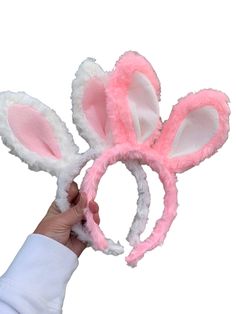 a hand holding two pink bunny ears on top of it's head with white fur