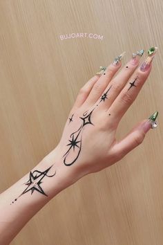 a woman's hand with tattoos on it and stars around the wrist, holding onto a wooden wall