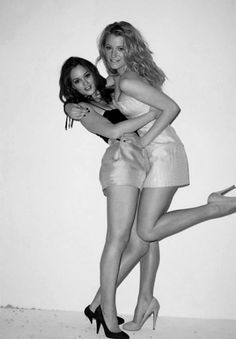 two young women are hugging and posing for the camera