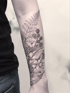 a person with a black and white tattoo on their arm is holding onto a plant