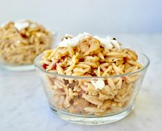 two glass bowls filled with food sitting on top of a white countertop next to each other