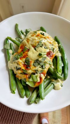 a white plate topped with green beans covered in sauce