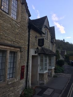 an old stone building on the side of a road with lots of windows and doors