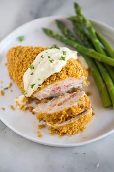 a white plate topped with meat and asparagus